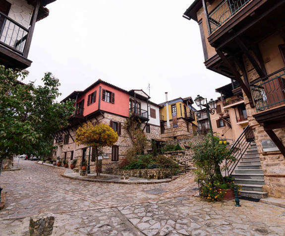 Arnea traditional village square with stone-paved streets and wooden-balcony houses