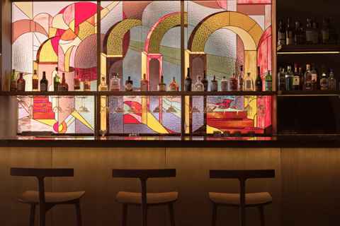 Stylish bar with colorful stained glass backdrop and premium spirits at Eagles Club