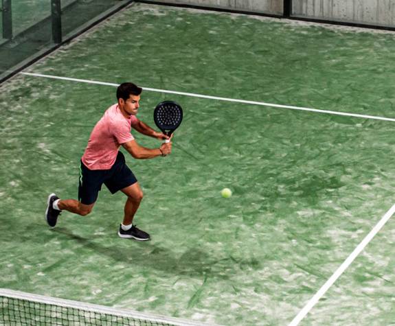 Man playing a match on a green padel court at Eagles Resort