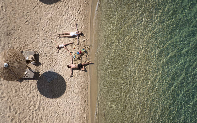 Aerial view of sandy beach with a relaxed family at the sea shore