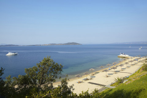 Eagles Resort Chalkidiki sandy beach with trees and umbrellas and sailing boats