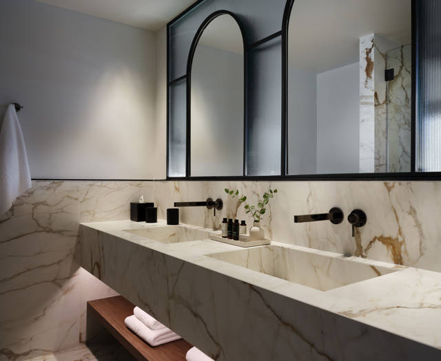 Executive junior suite's marble bathroom with dual sinks and arched mirrors with black frames