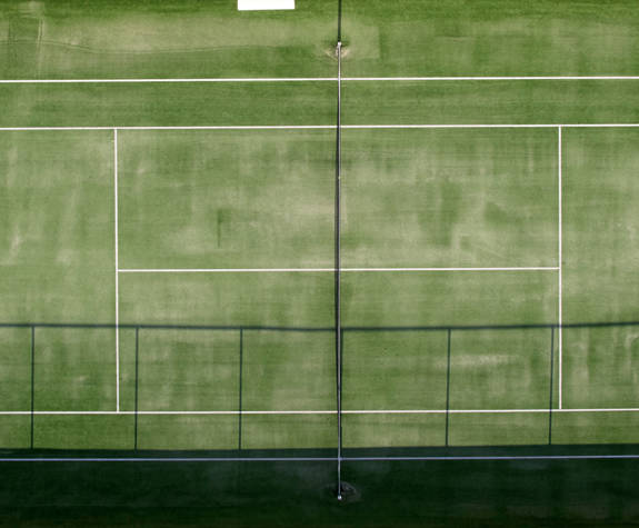 Top down view of a tennis court with two players in action at Eagles Resort