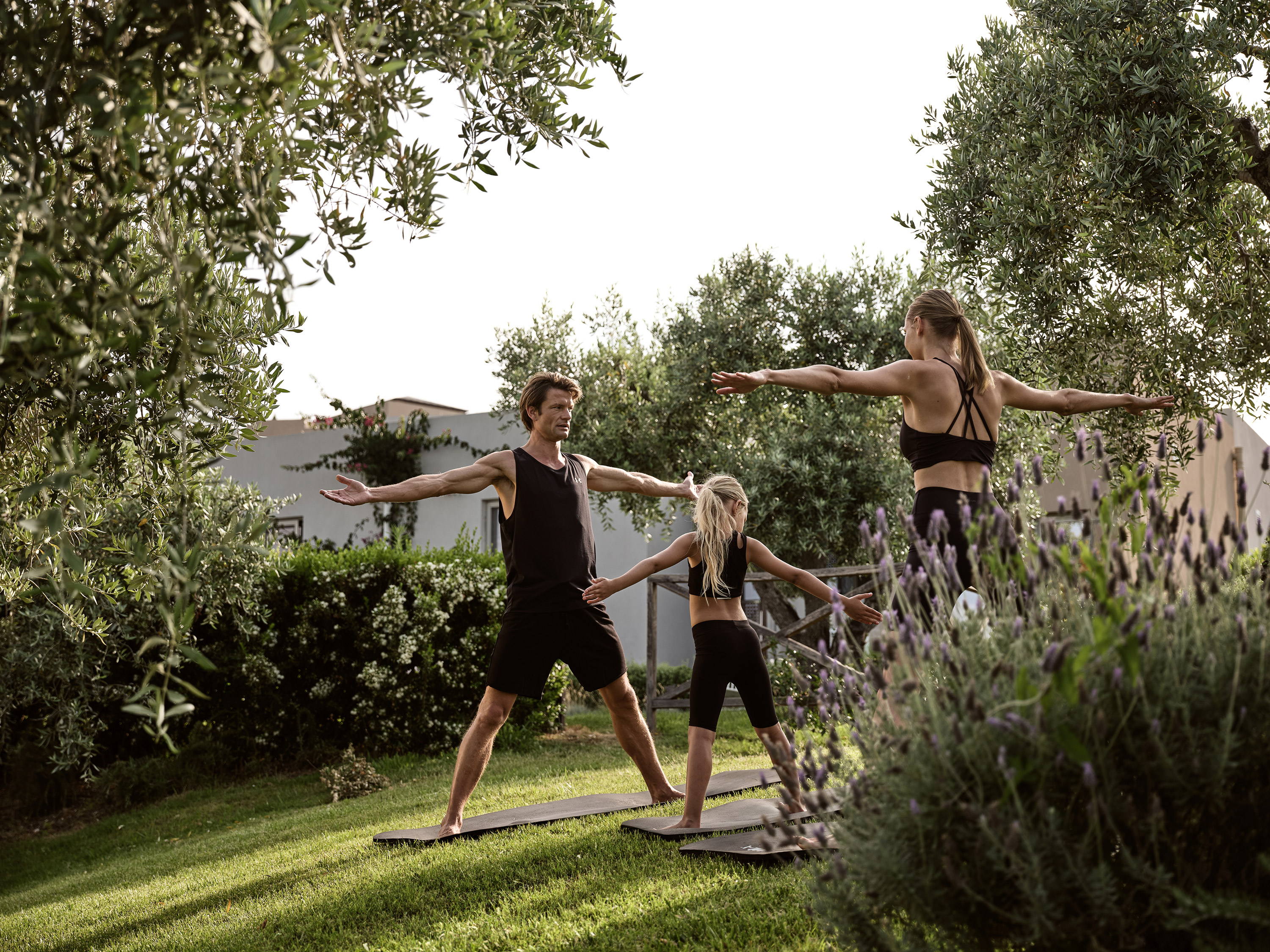 Family enjoying an outdoor yoga session surrounded by olive trees at Eagles Resort