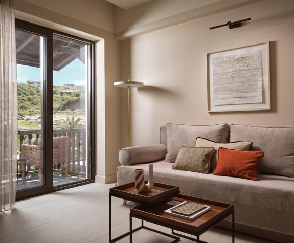 Deluxe suite living area  with sofa seating, coffee table and balcony doors overlooking the garden in Eagles Palace