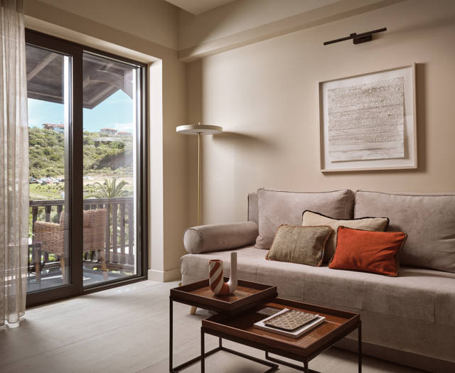 Deluxe suite living area  with sofa seating, coffee table and balcony doors overlooking the garden in Eagles Palace