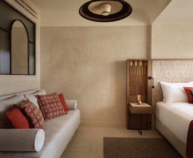 Executive junior suite with sofa and terracotta cushions, bedside table with reading light and textured headboard