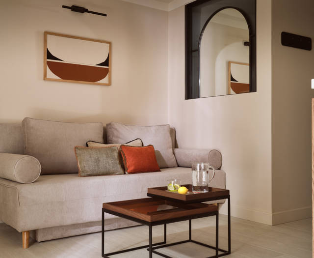 Deluxe family suite with modern sitting area and wall-mounted arched mirror in Eagles Resort
