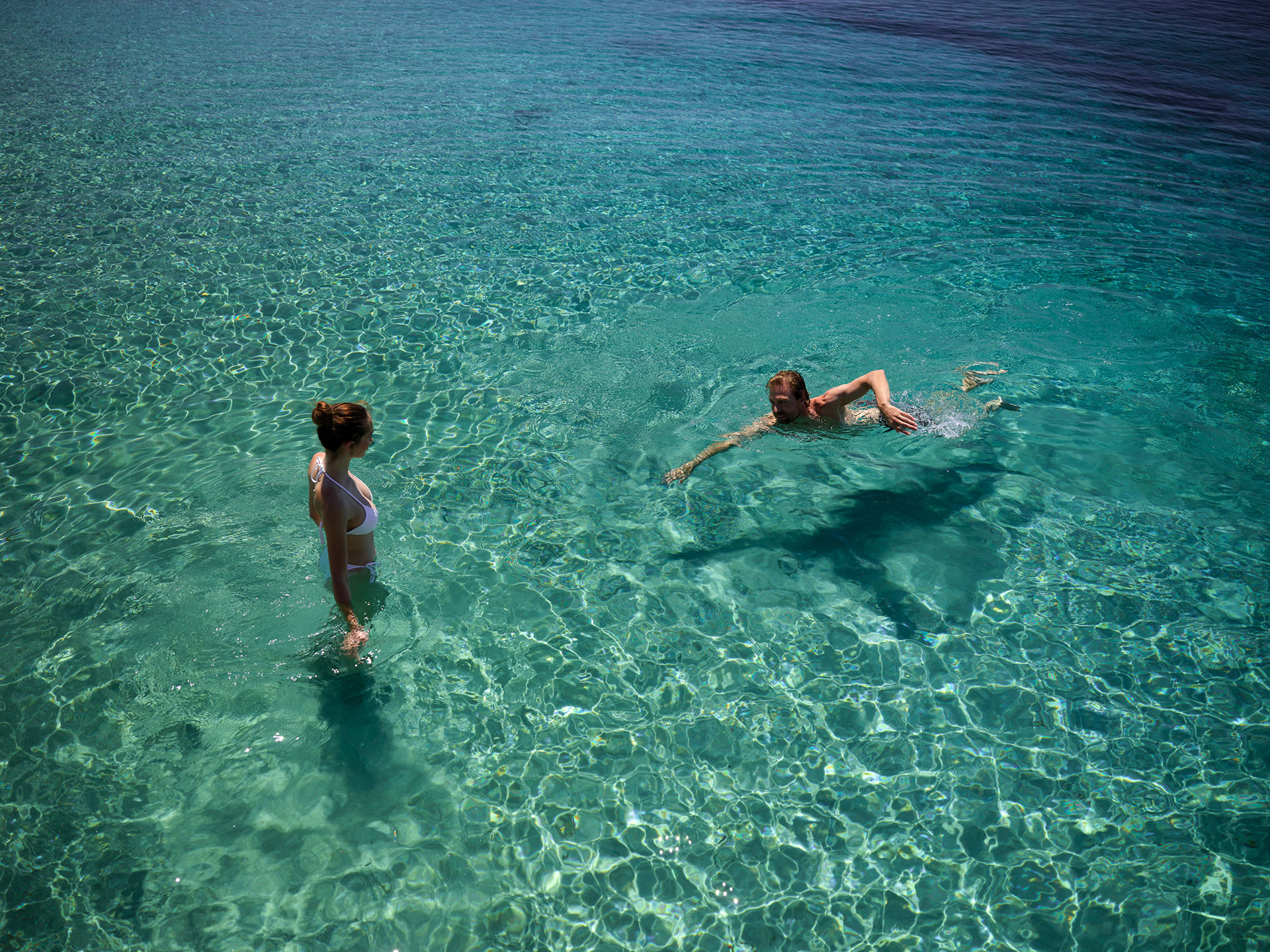 Couple enjoying swimming in the crystal clear waters of the beach at Eagles Resort