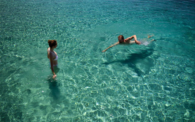Couple enjoying swimming in the crystal clear waters of the beach at Eagles Resort