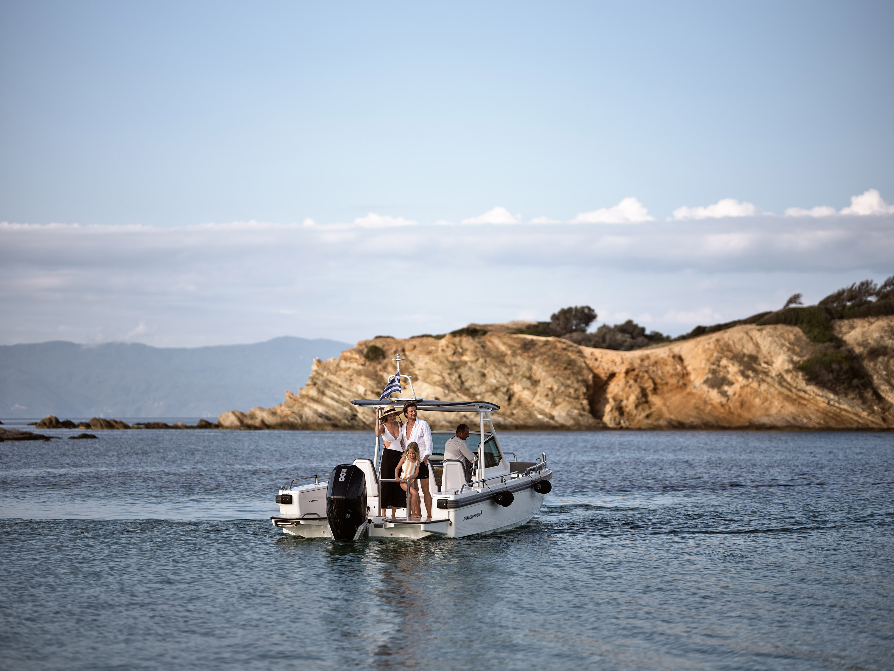 Small motorboat cruising near rocky coastline with people onboard