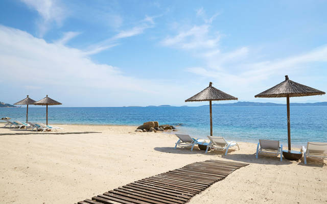 Sandy beach sea shore with umbrellas and sun loungers at Eagles Resorts