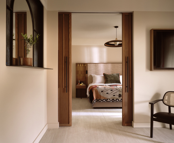 Deluxe suite at Eagles Palace with sliding wooden doors to the bedroom, cane chair and wall mirror