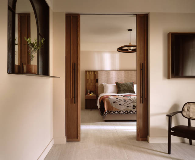 Deluxe suite at Eagles Palace with sliding wooden doors to the bedroom, cane chair and wall mirror
