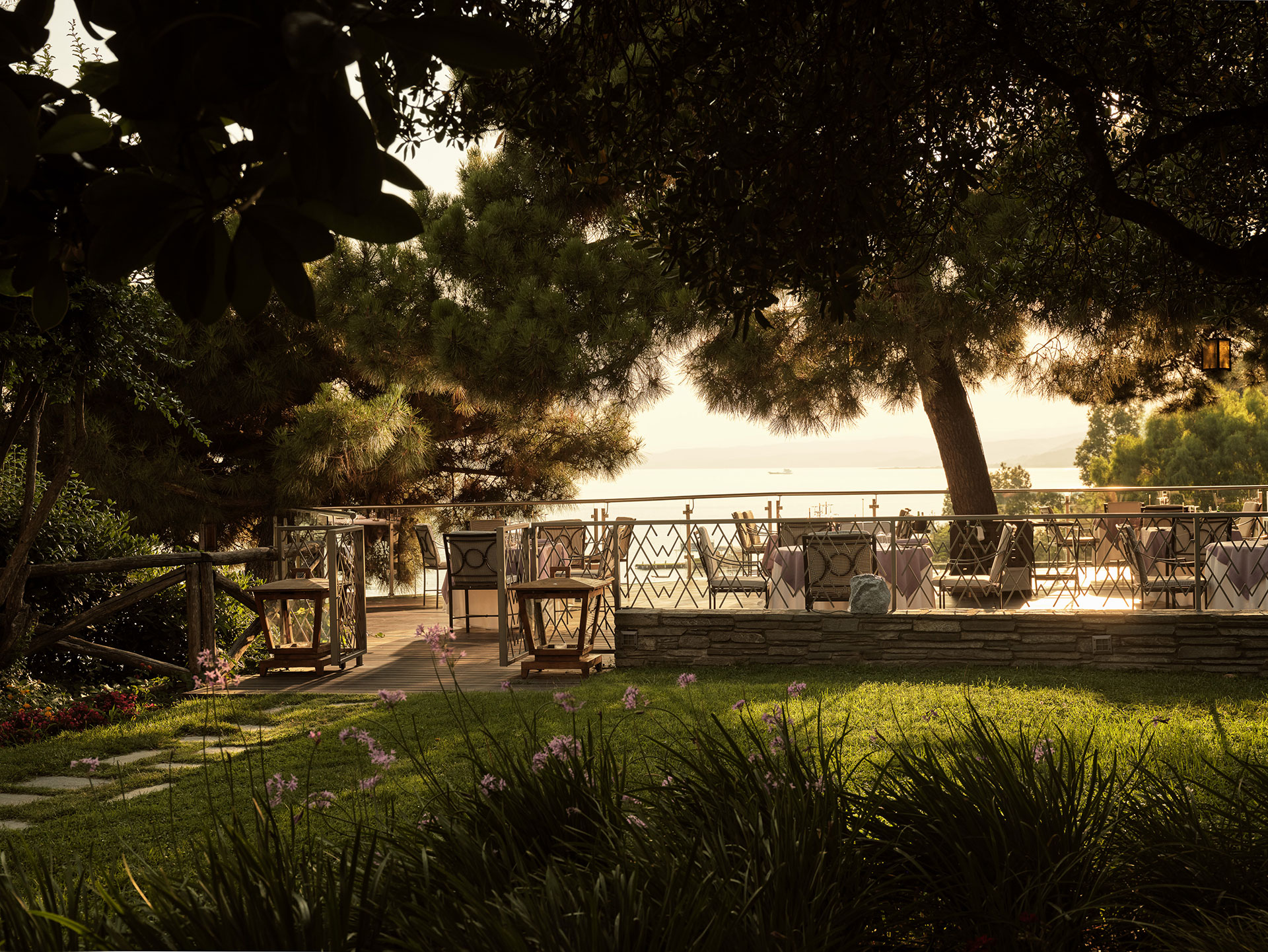 Outdoor dining terrace of Kamares restaurant with sea view and pine trees at Eagles Resort