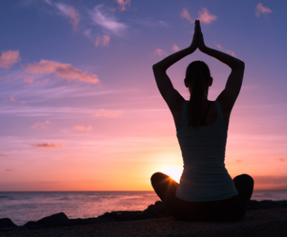 Woman practicing yoga at sunset by the sea at Eagles Resort
