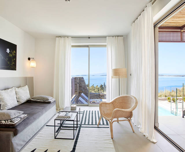 One bedroom villa living room with sofa, armchair and sliding doors to terrace with sea view at Eagles Villas