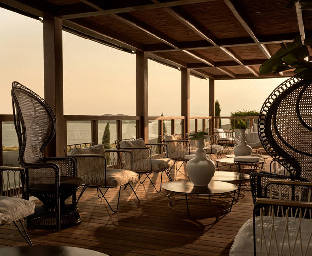 Cabin bar covered terrace with modern furnishing at dusk overlooking the sea at Eagles Resort