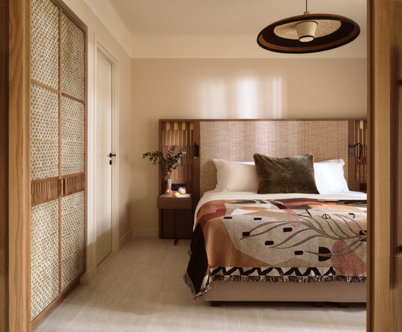 Deluxe suite bedroom at Eagles Palace with textured headboard, patterned bed throw and wooden wardrobe panels