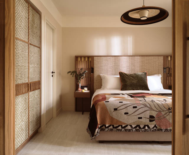 Deluxe suite bedroom at Eagles Palace with textured headboard, patterned bed throw and wooden wardrobe panels